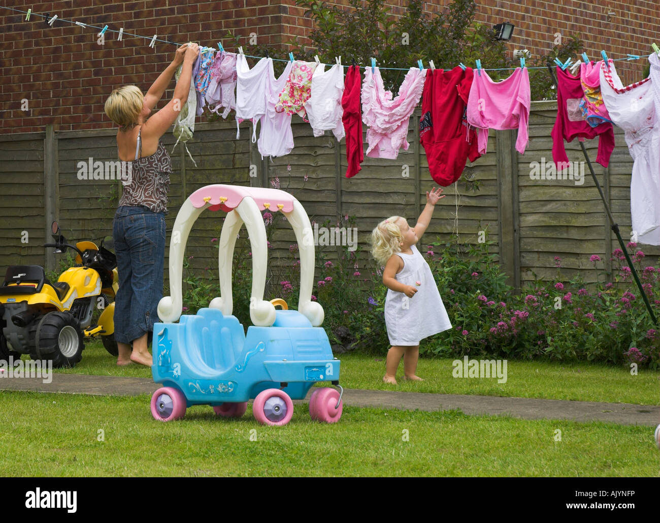 Little girl 'helps' mummy hang out the washing. Stock Photo