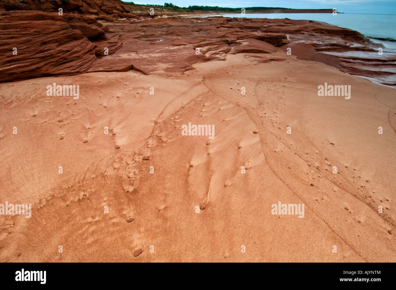 Beach sand and red rocks with runoff patterns, Campbell's Cove, PE/PEI Prince Edward Island, Canada Stock Photo