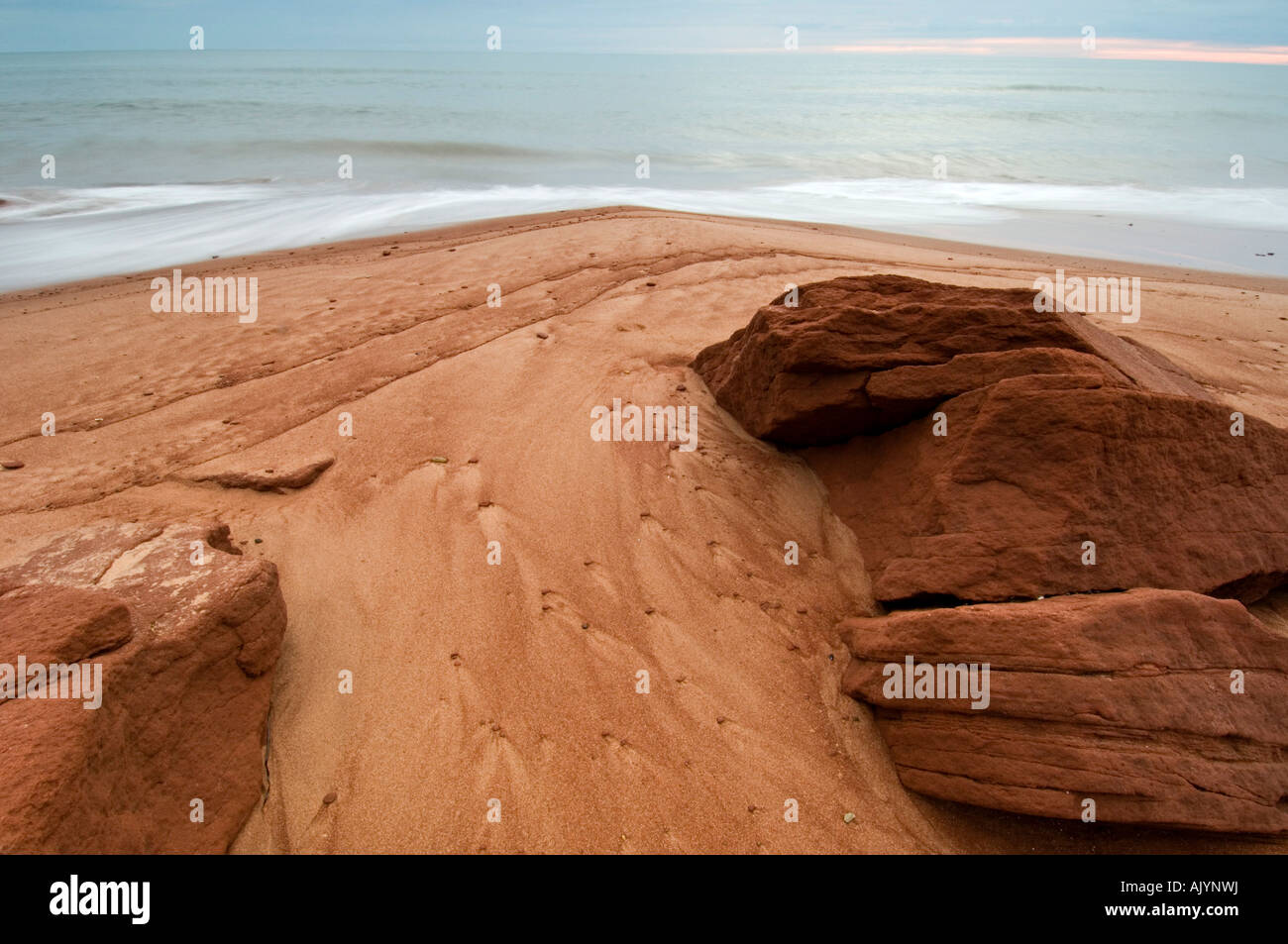 Beach sand and red rocks with runoff patterns, Campbell's Cove, PE/PEI Prince Edward Island, Canada Stock Photo