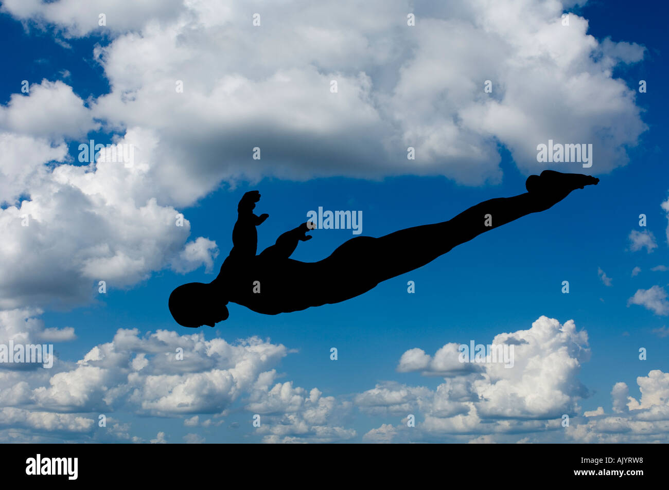 silhouette of man diving with background of blue sky and white clouds Stock Photo
