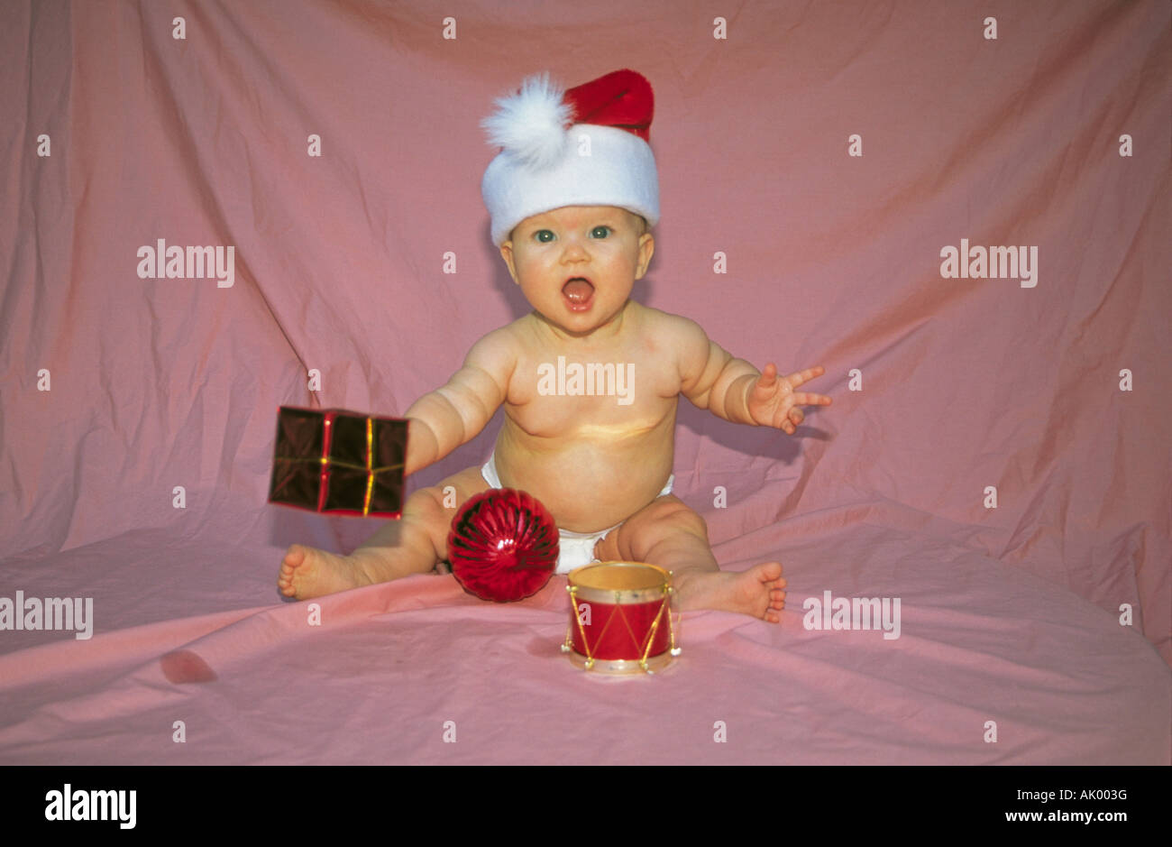 USA ARKANSAS HOT SPRINGS A baby girl wearing a Santa Clause Hat plays with ornaments at Christmas Stock Photo