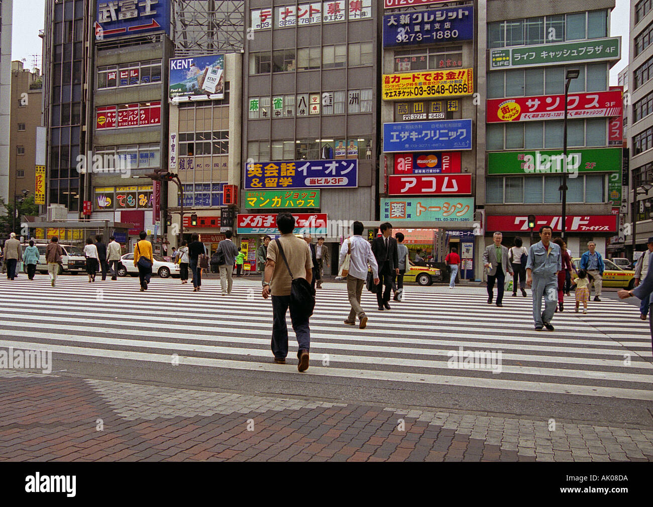 Busy zebra crossing man woman commuter walk shopping centre colourful sign traffic light Ginza Tokyo Japan Eastern Asia Stock Photo