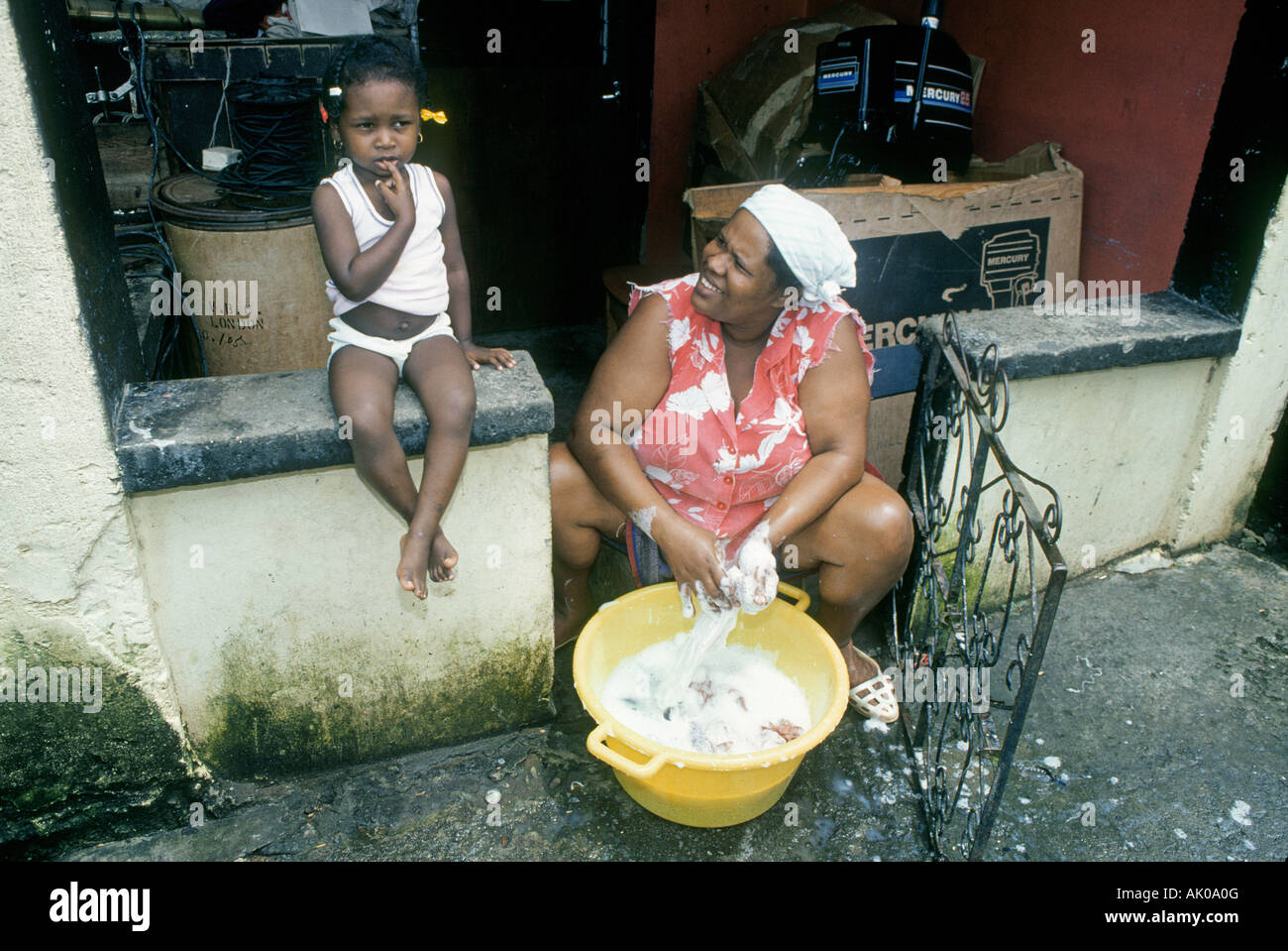 A mother and her daughter wash the family s clothes in a village along the North coast of Grenada Stock Photo
