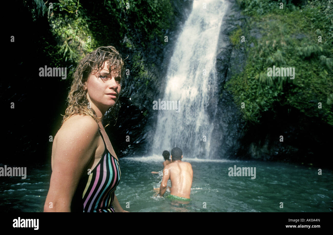 A group of visitors swim in an icy stream below Concorde Falls a beautifuyl waterfall in the mountains of Grenada Stock Photo
