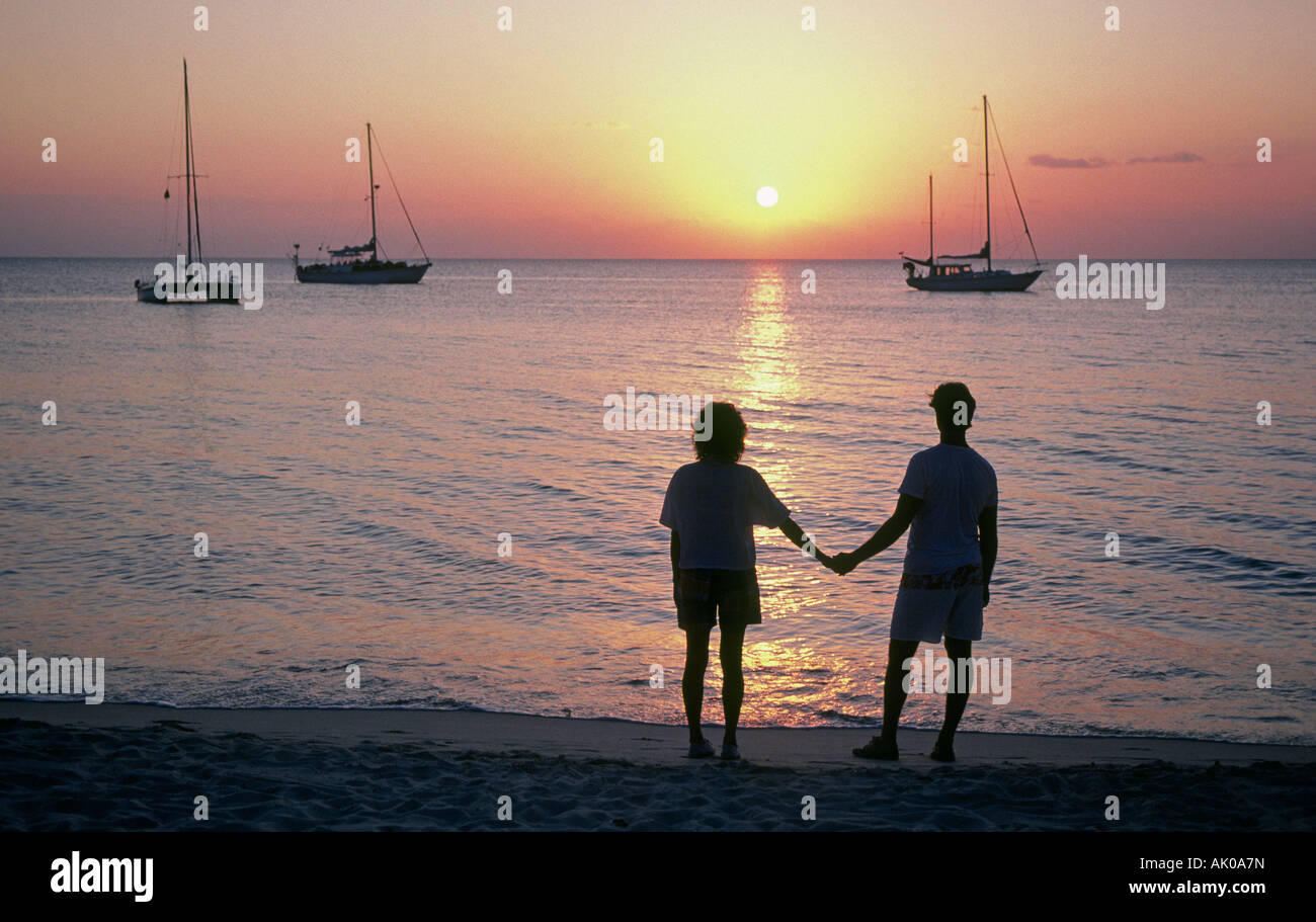A young couple wander along a Grenada beach at sunset Stock Photo