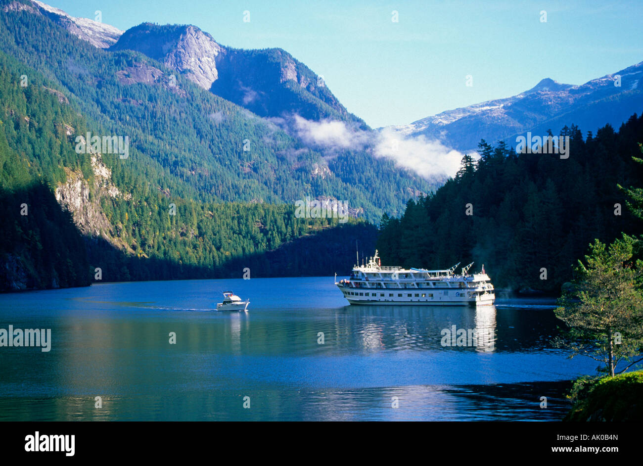 A small cruise ship navigates the waters of Princess Louisa Inlet the Inside Passage in British Columbia Stock Photo
