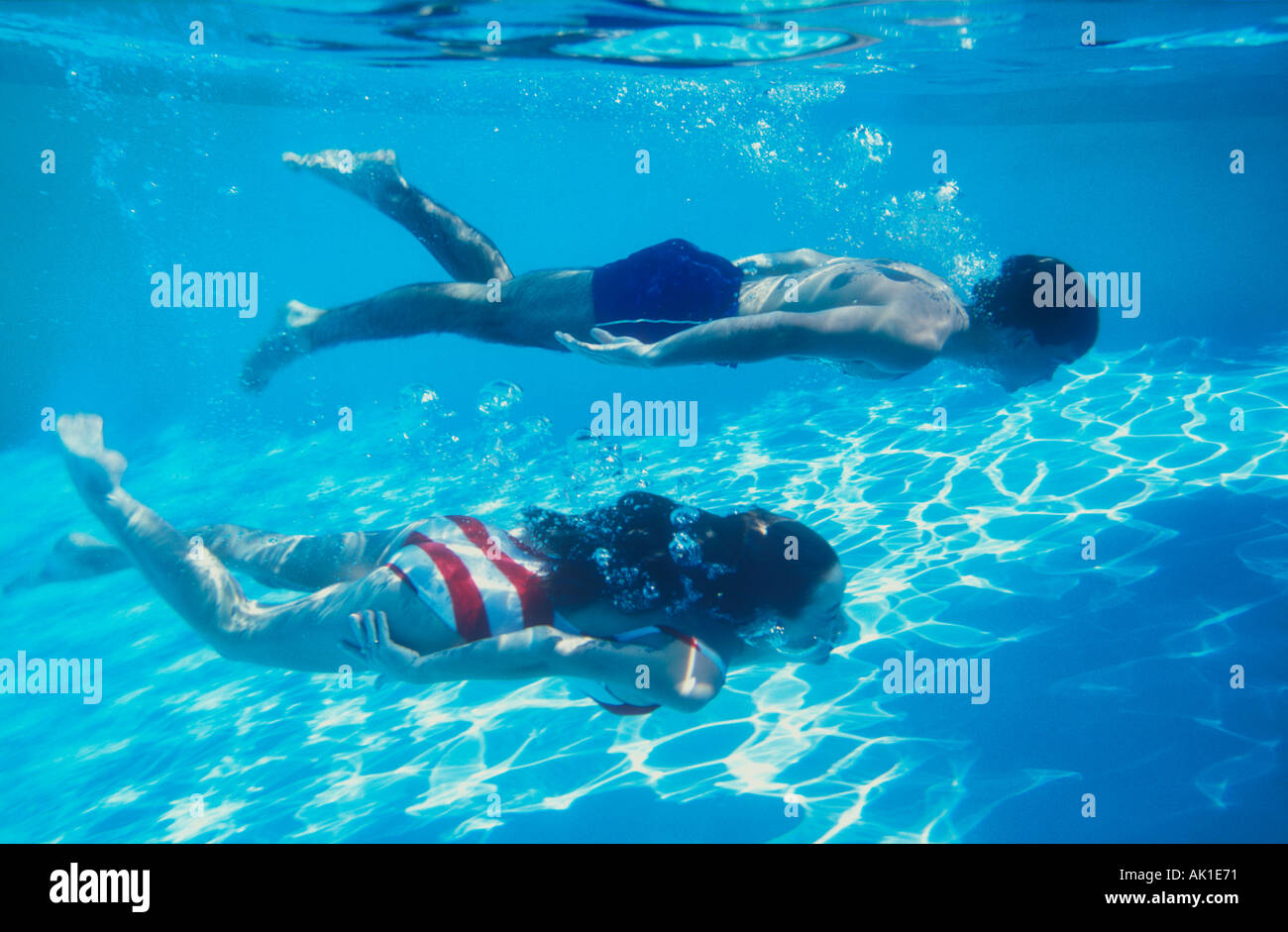 couple swimming underwater in pool Stock Photo