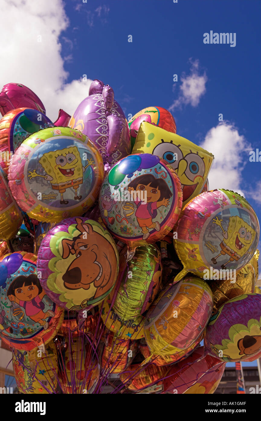 Colourful helium character balloons with smiling faces against blue sky Stock Photo