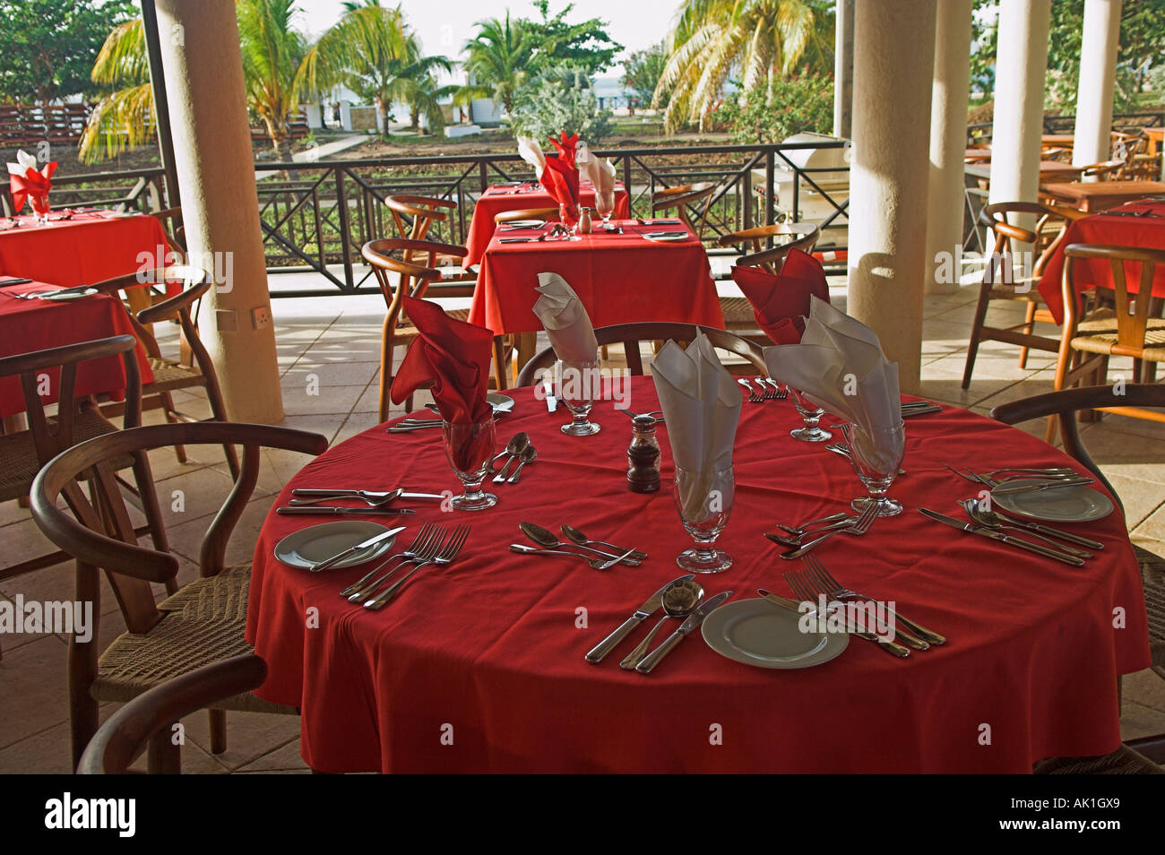 Round table in terrace restaurant set for dinner with red tablecloths