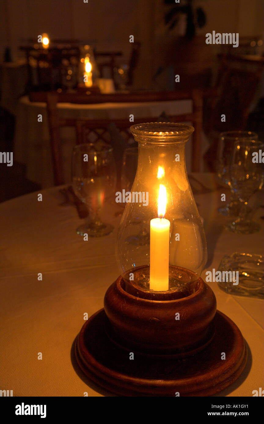 Glow of lit candle in candleholder with empty wine glass ready for dinner Stock Photo