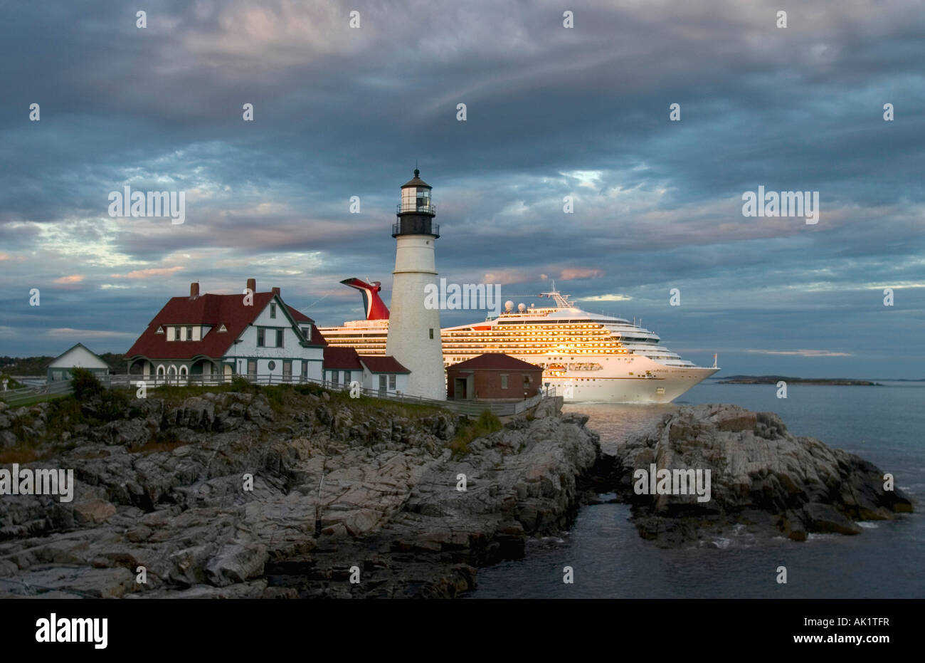 Portland Maine The luxury cruise liner Carnival Victory passes off Portland Head Lighthouse at dusk all lights blazing Stock Photo