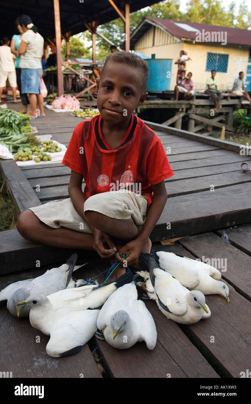 Asmat boy selling wild pigeons for food, Agats Irian Jaya Indonesia. Stock Photo