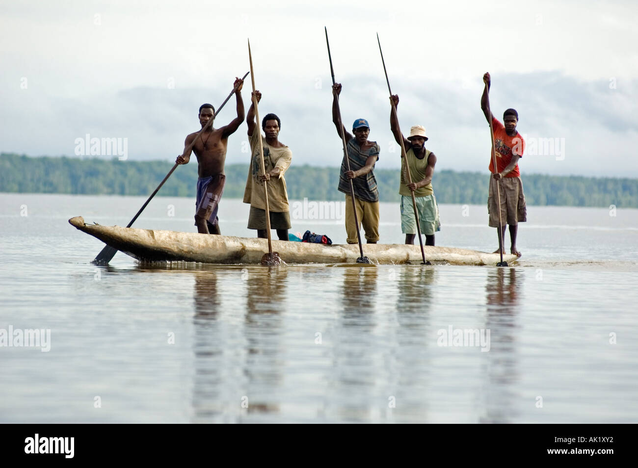 Asmat men paddling in their dugout canoe, Irian Jaya Indonesia. Stock Photo