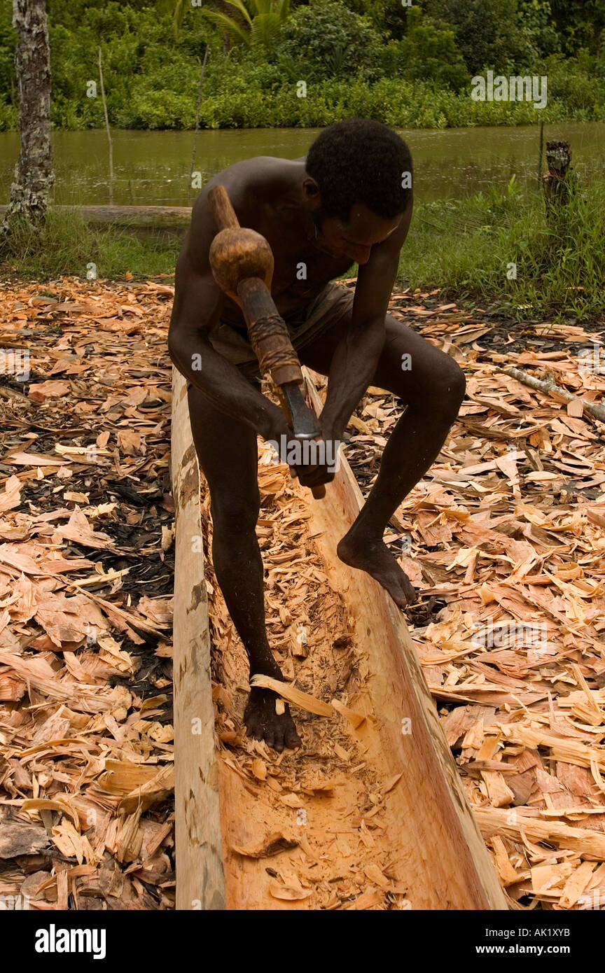 Asmat tribal man building a dugout canoe, Irian Jaya, Indonesia. Stock Photo