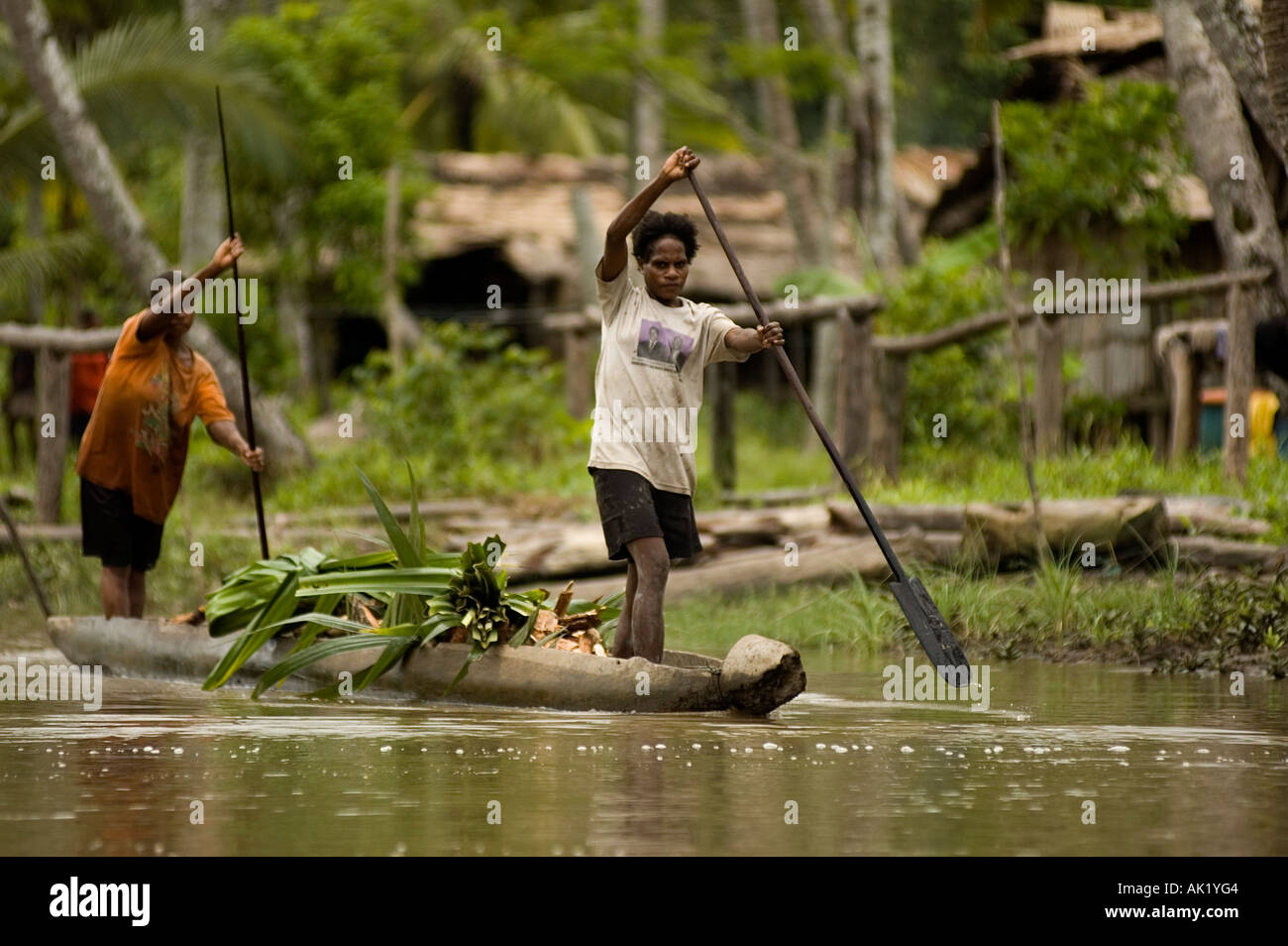 Hunter gatherer Asmat people in a dugout canoe, Irian Jaya Indonesia. Stock Photo