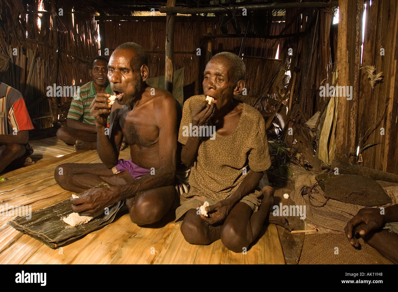 Elder Asmat couple eating staple food of sago, Irian Jaya, Indonesia. Stock Photo