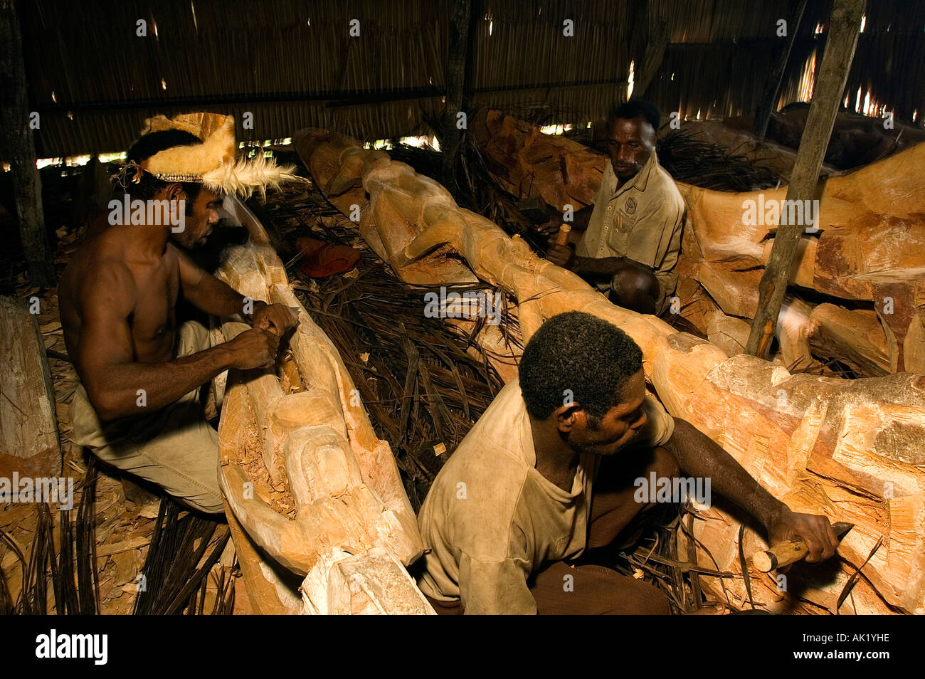 Asmat tribal men carving totem poles in Omandeseb Village, Irian Jaya, Indonesia. Stock Photo