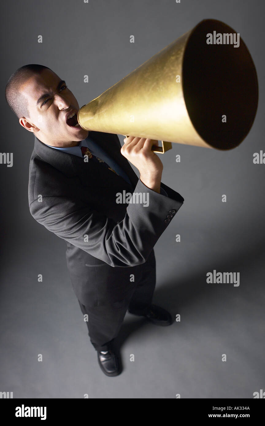 Angry businessman yelling into bullhorn Stock Photo