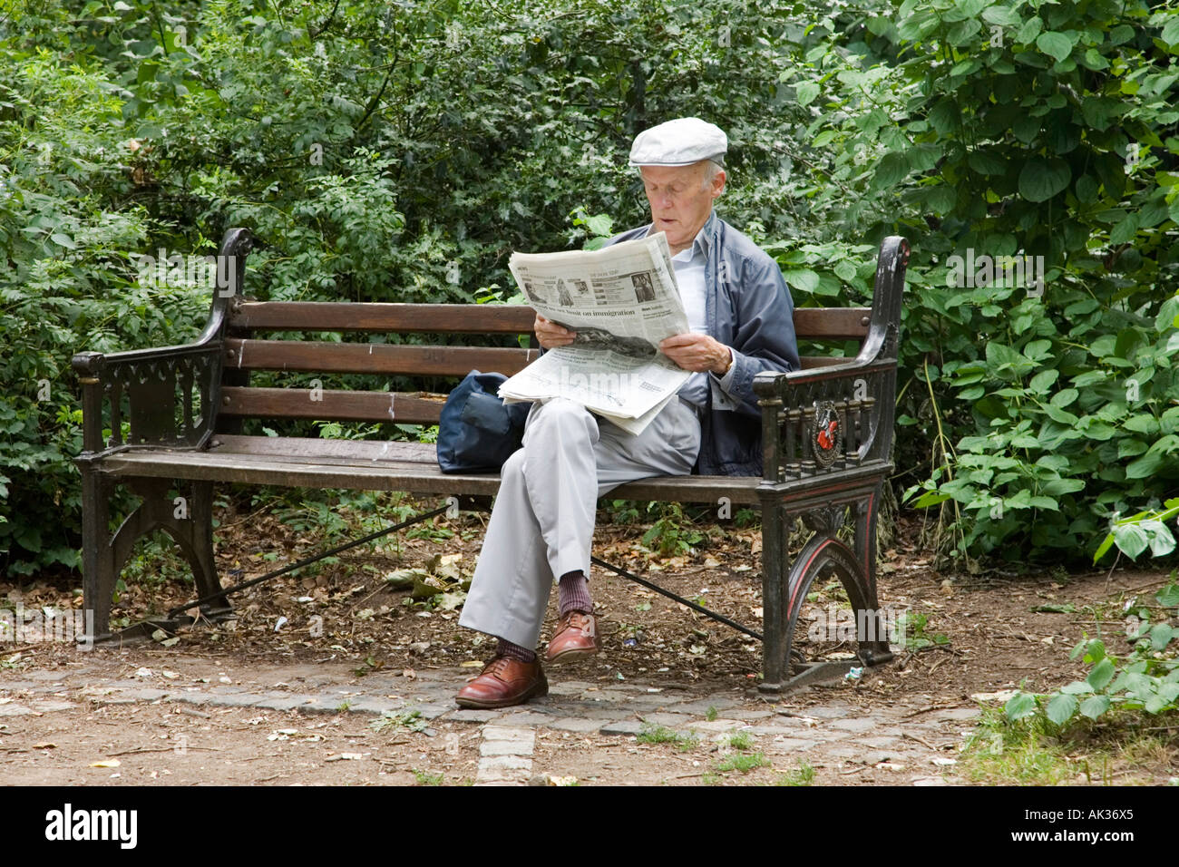 an old man reading a newspaper in a park Stock Photo