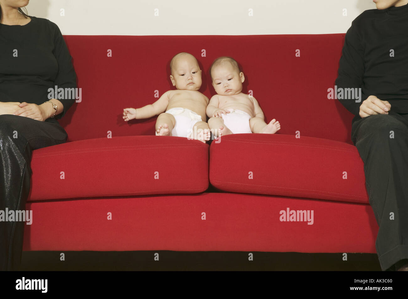 Twin babies sitting between their parents Stock Photo Alamy