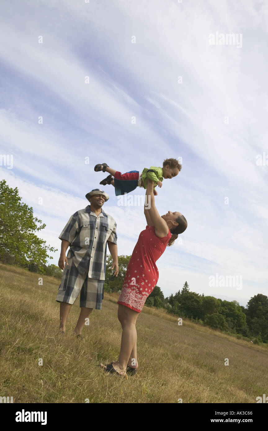 A couple playing with their son in grassy field Stock Photo