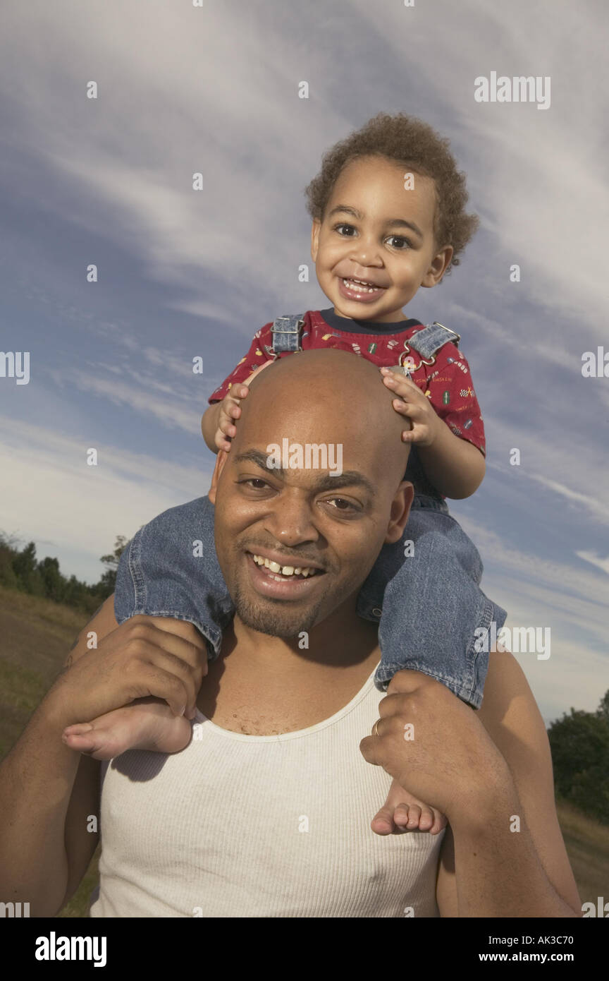 A toddler riding on his father s shoulders Stock Photo