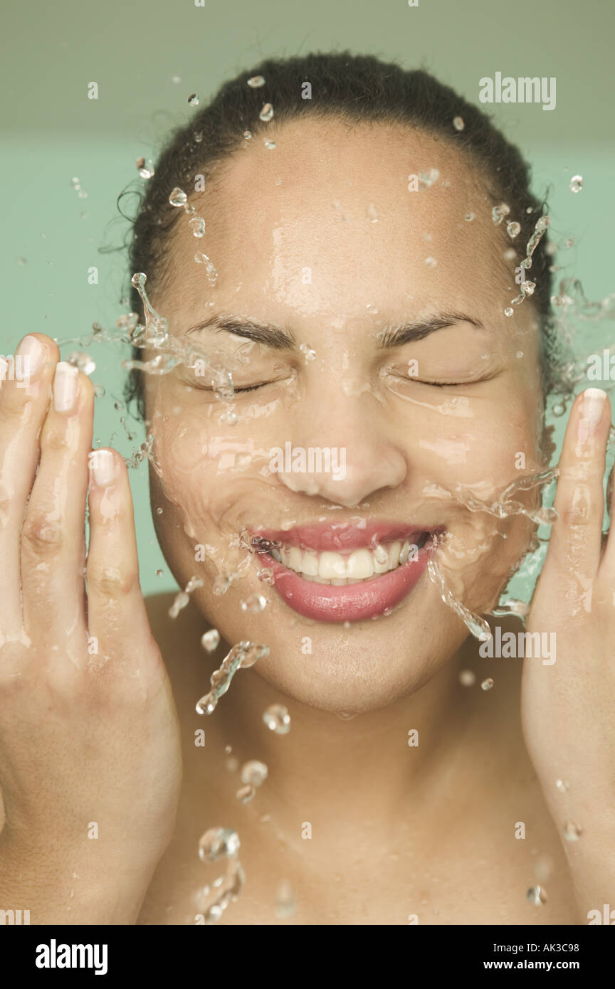 A smiling woman washing her face Stock Photo