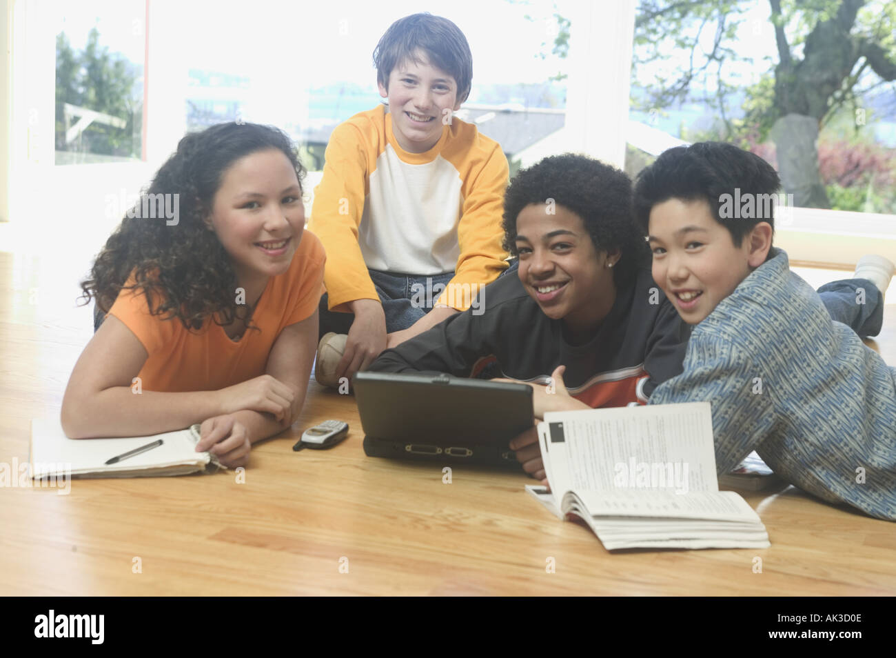Four teenage kids working on a laptop and school books Stock Photo