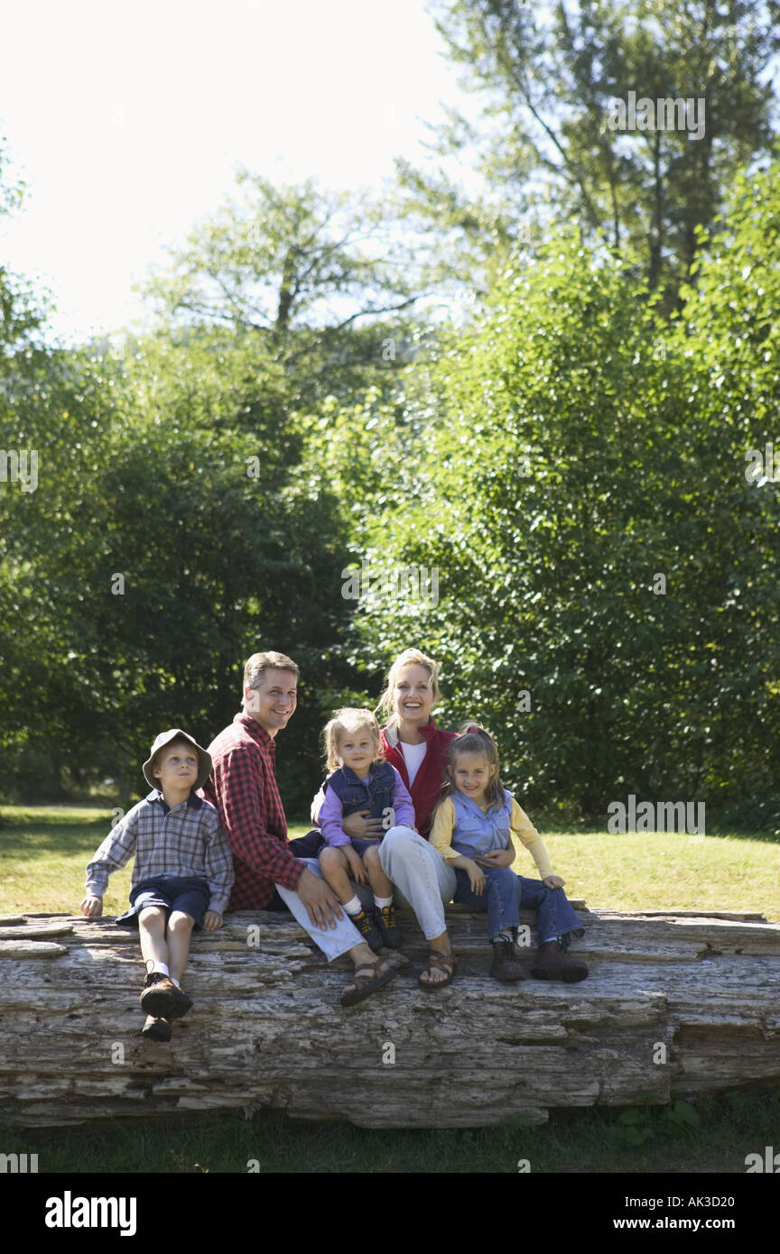 Portrait of a family of five sitting on a log Stock Photo