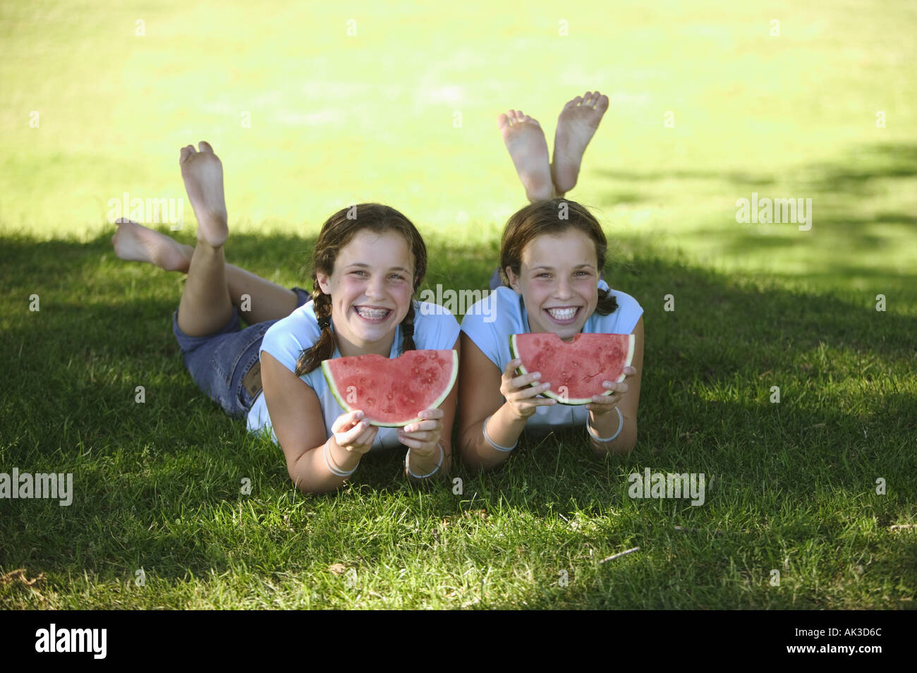 Twin teenage girls devouring slices of watermelon Stock Photo