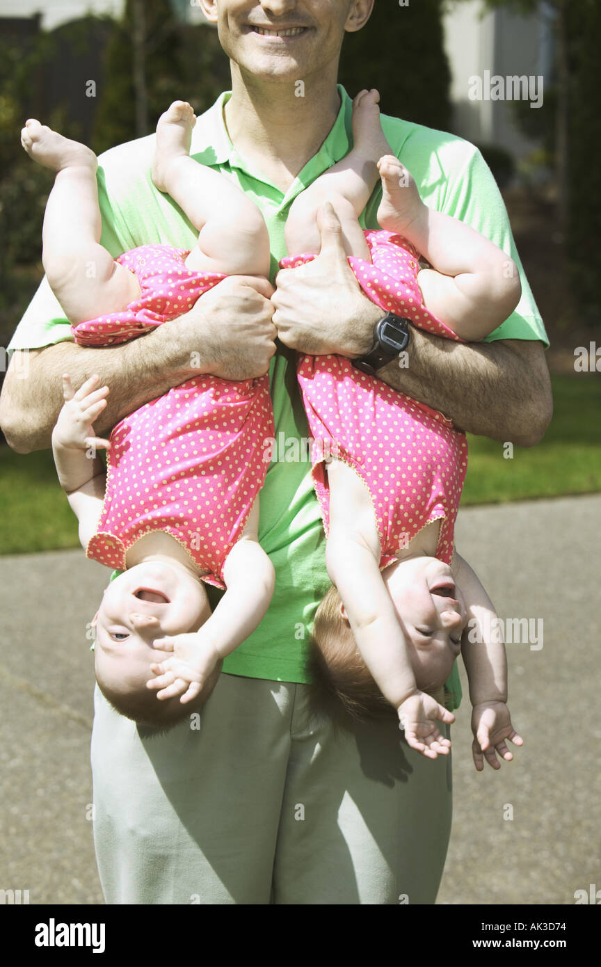 Father holding his twin babies upside down Stock Photo Alamy