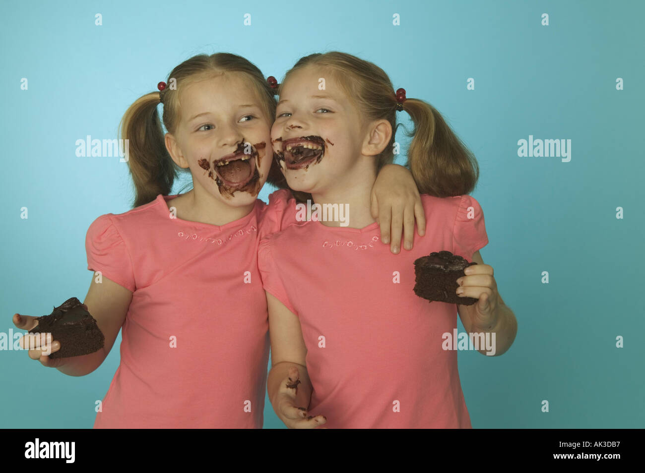 Twin girls eating chocolate cake Stock Photo