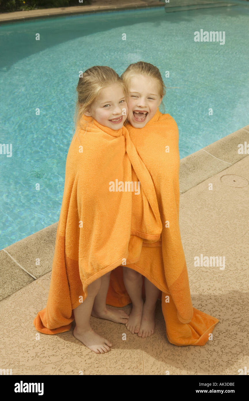 Young twin Caucasian girls share a towel poolside Stock Photo