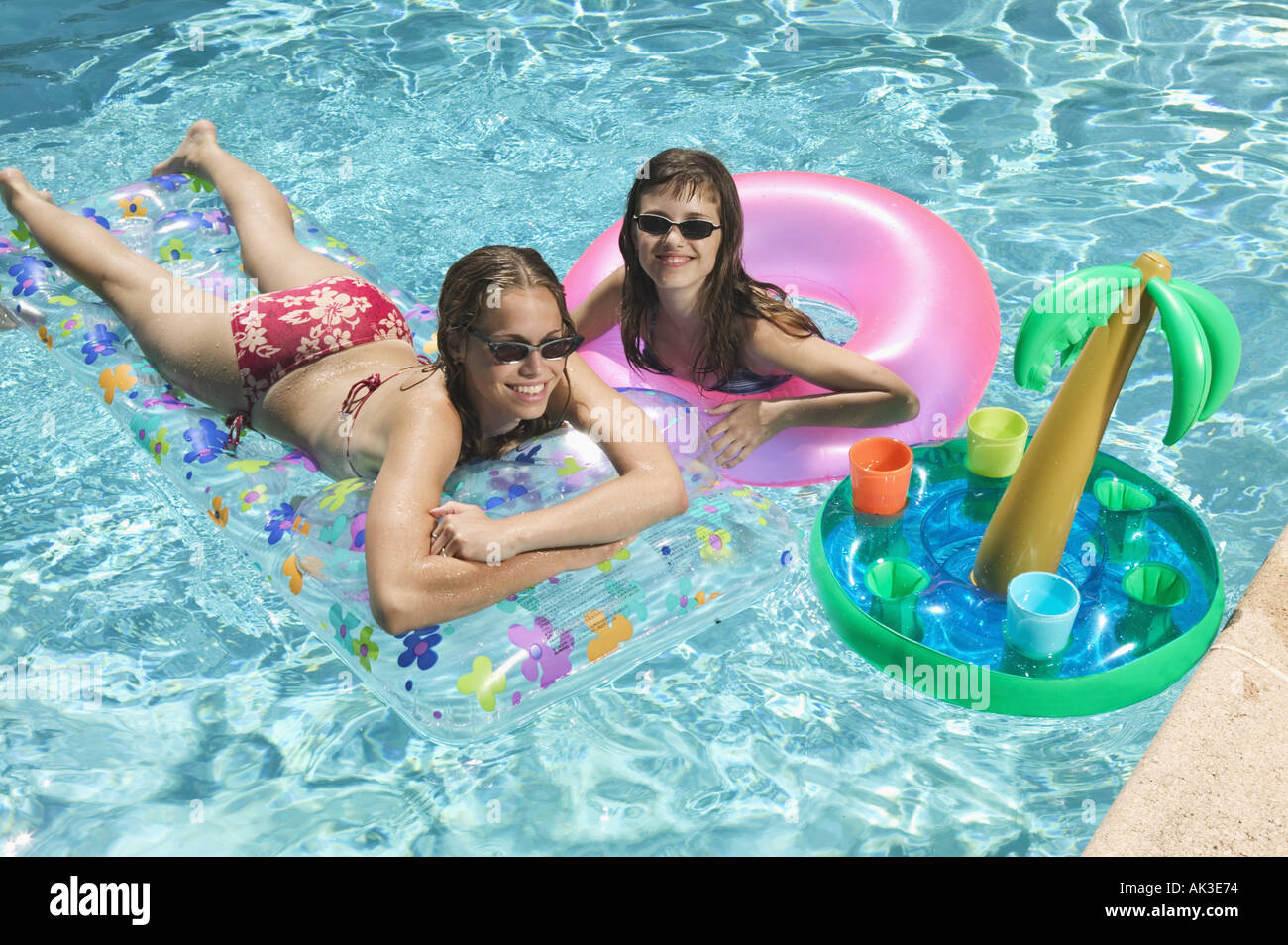 Two teenage girls lounging in a swimming pool Stock Photo
