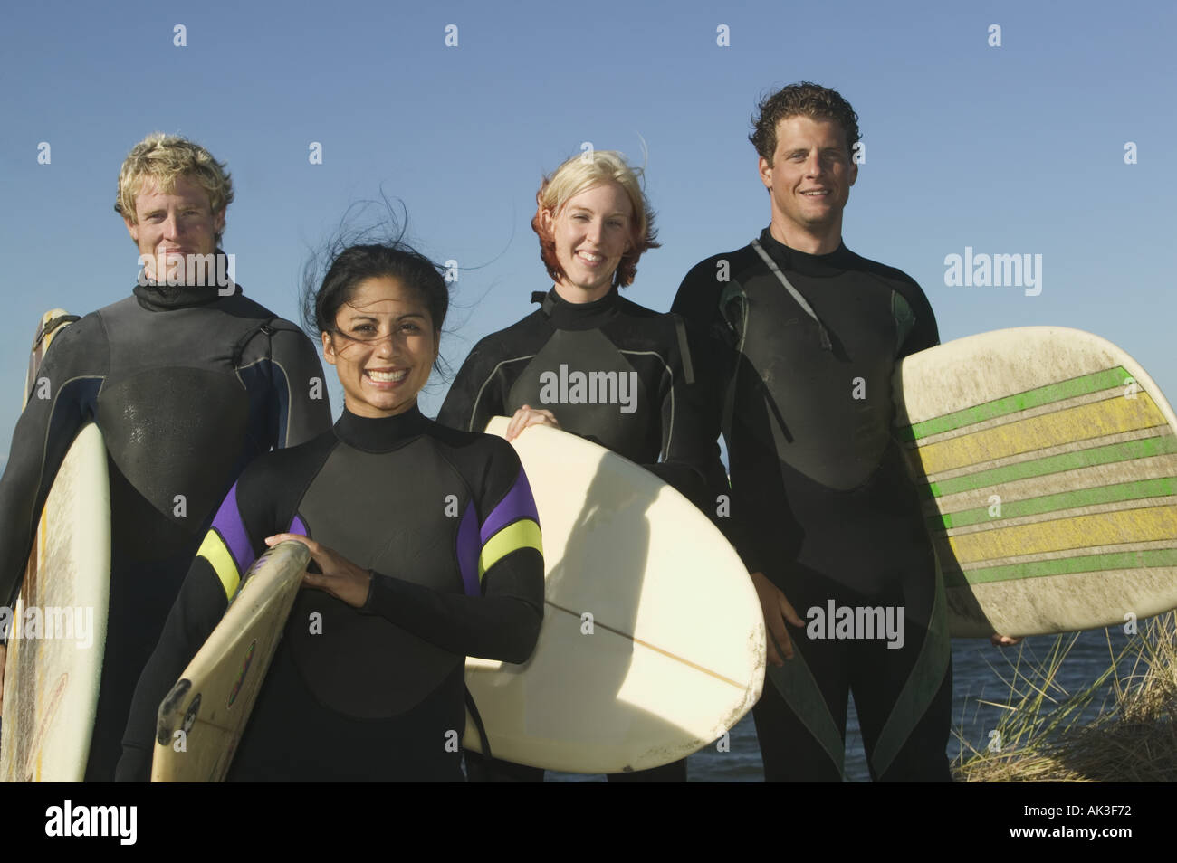 Portrait of four surfers in wetsuits Stock Photo