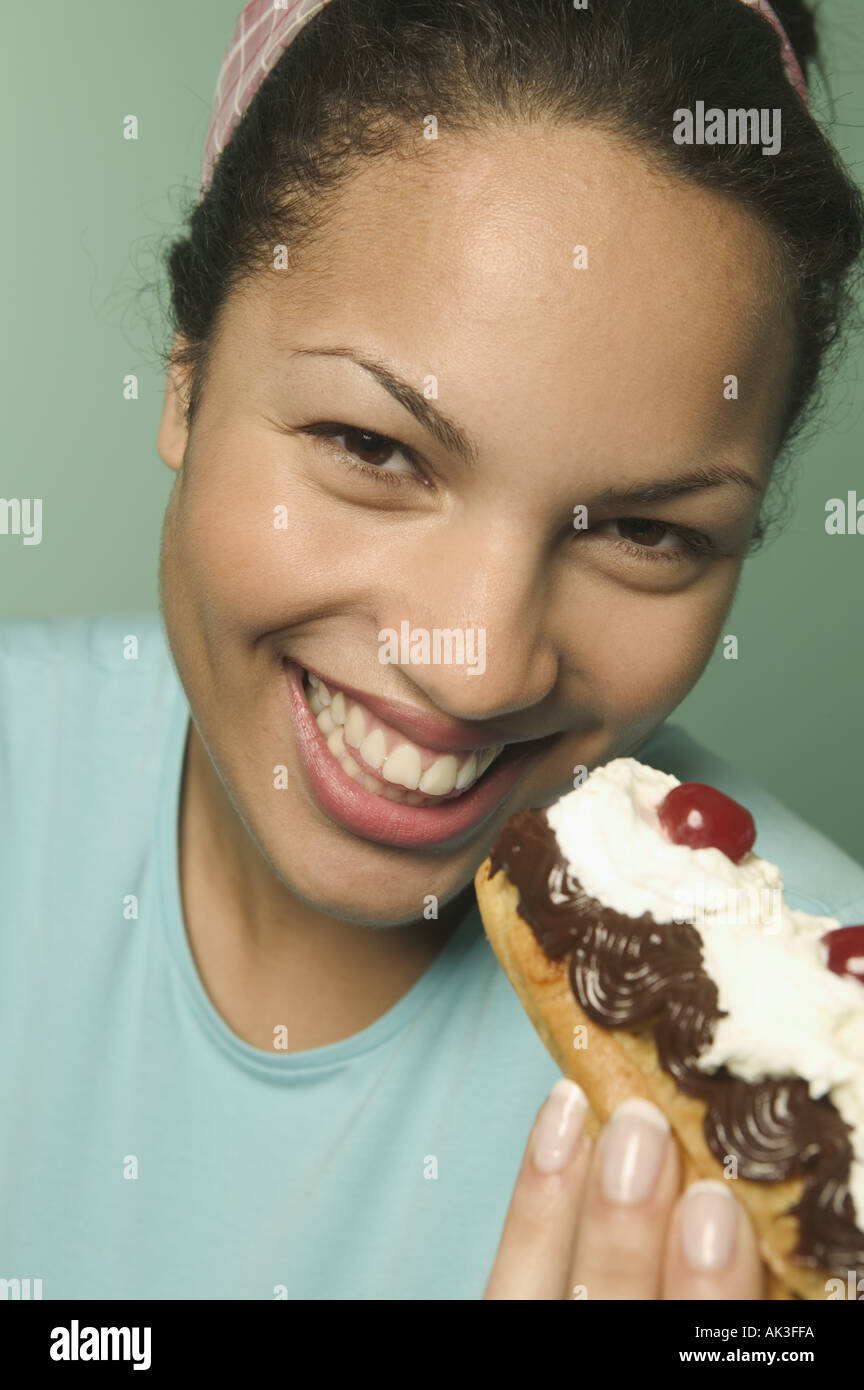 Young woman eating an eclair pastry Stock Photo