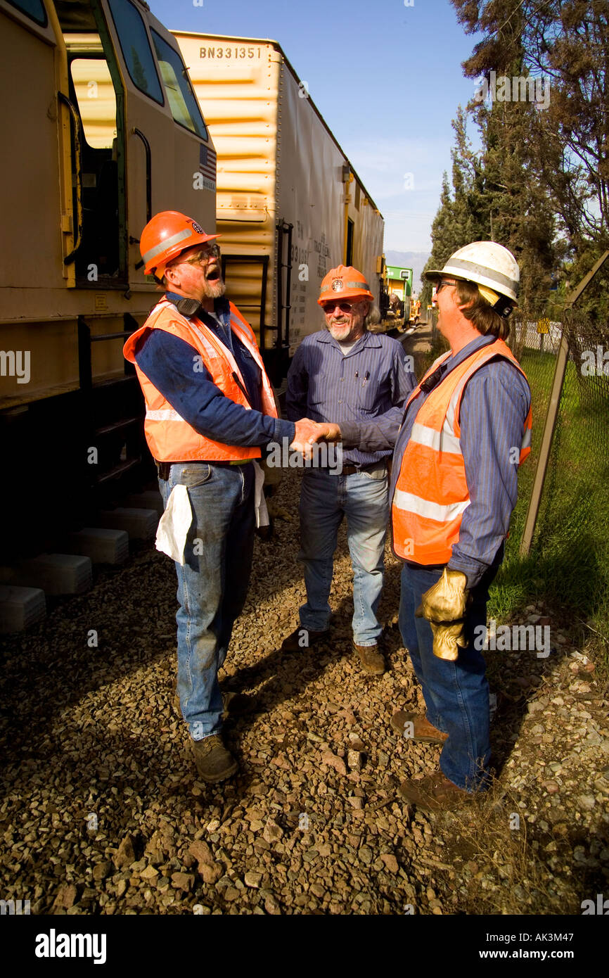 Two railroad maintenance men shake hands after a job well done repairing tracks in San