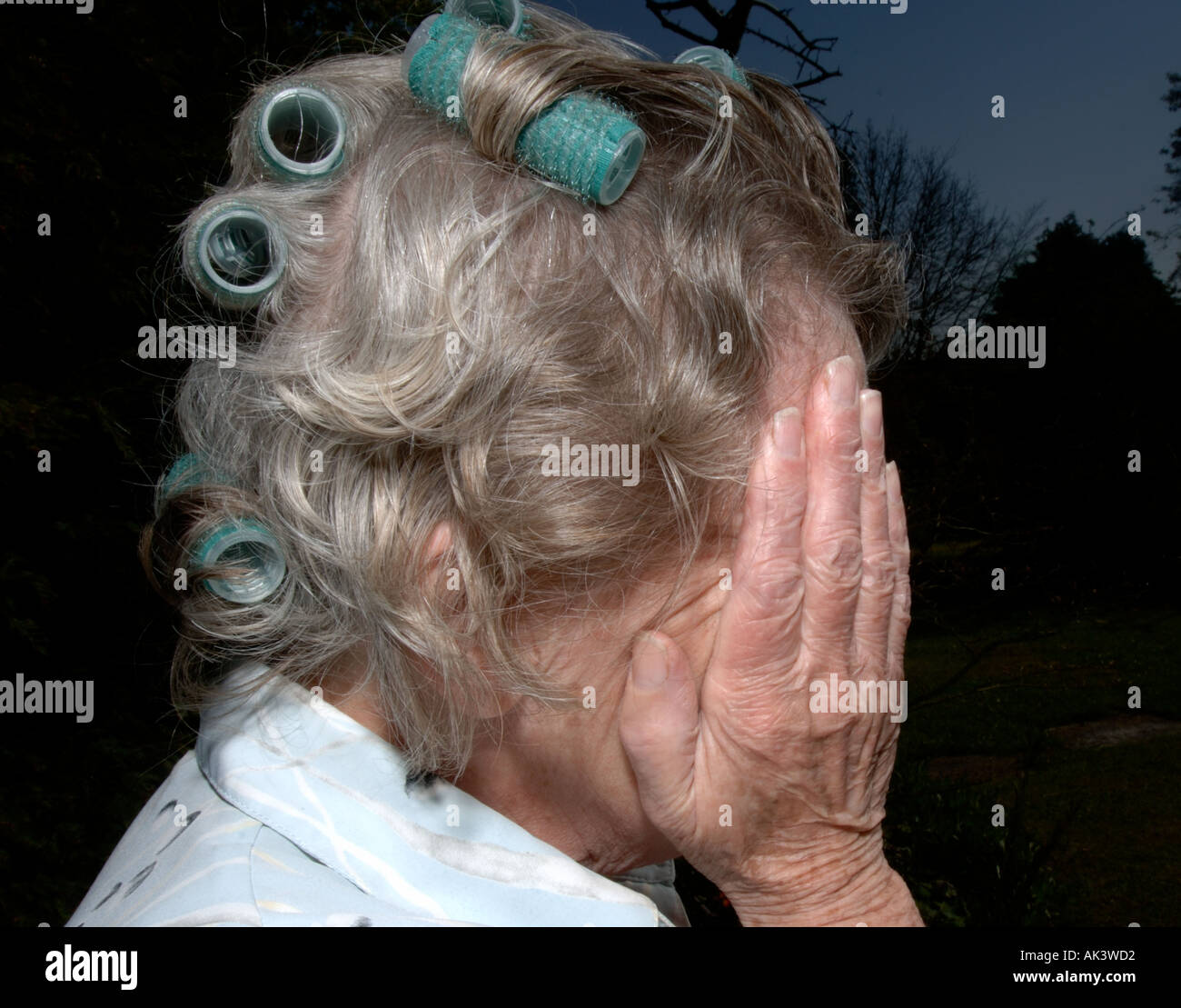 old lady in curlers in despair Stock Photo