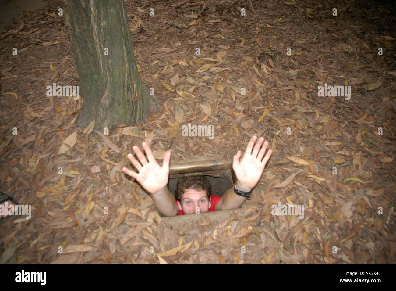 MR Man gets into the entrance of a cave in the ground Cu Chi Vietnam Stock Photo