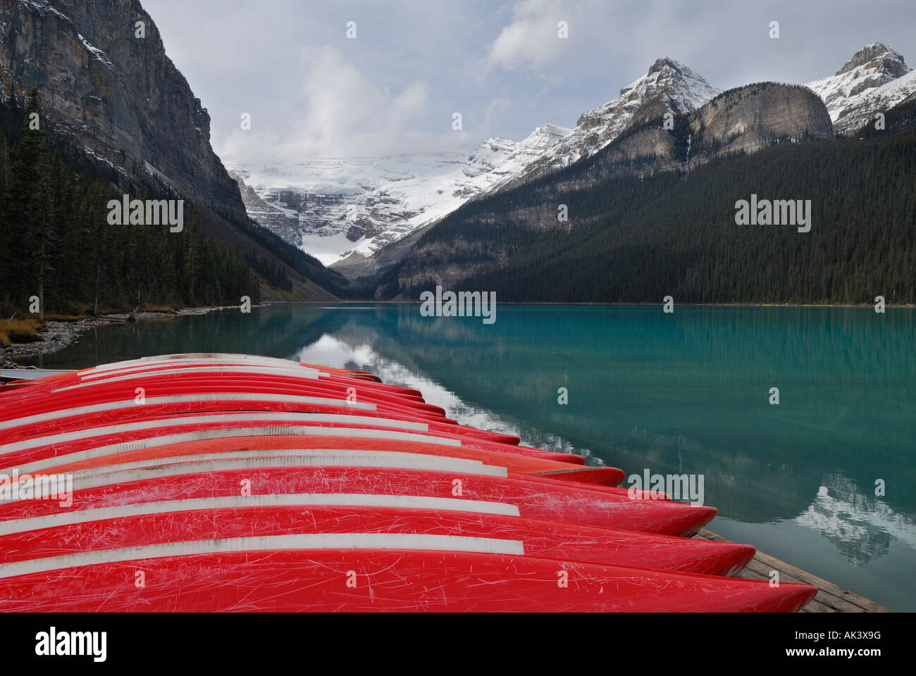 Beached red canoes at blue Lake Louise and snow on Canadian Rocky Mountains Banff National Park Alberta Canada Stock Photo