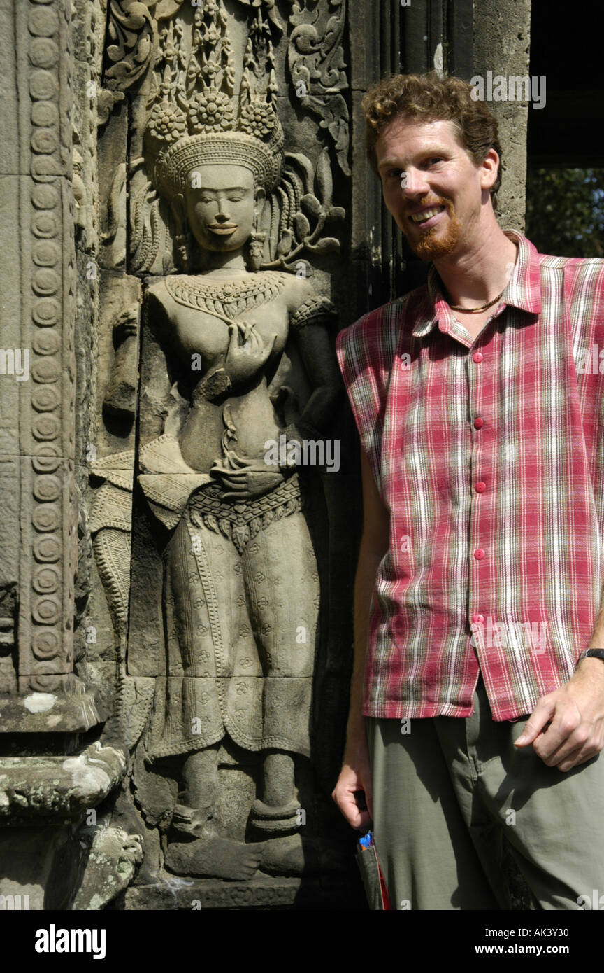 MR tourist is standing beside a stone relief of fine arts showing a charming apsera temple dancer at temple Thommanon Angkor Stock Photo