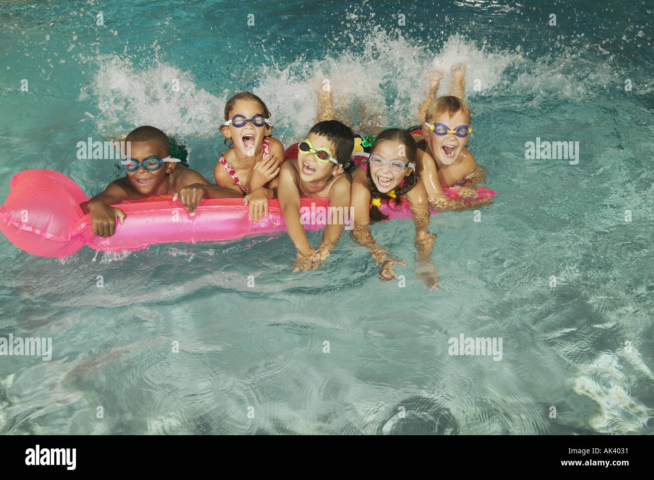 Group of kids in goggles on a pink float in a pool Stock Photo