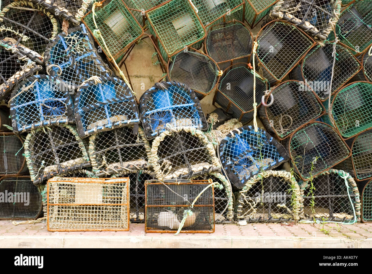 Crayfish or lobster pots are stacked against a wall in Getaria's harbour on the Basque Coast of Spain. Stock Photo