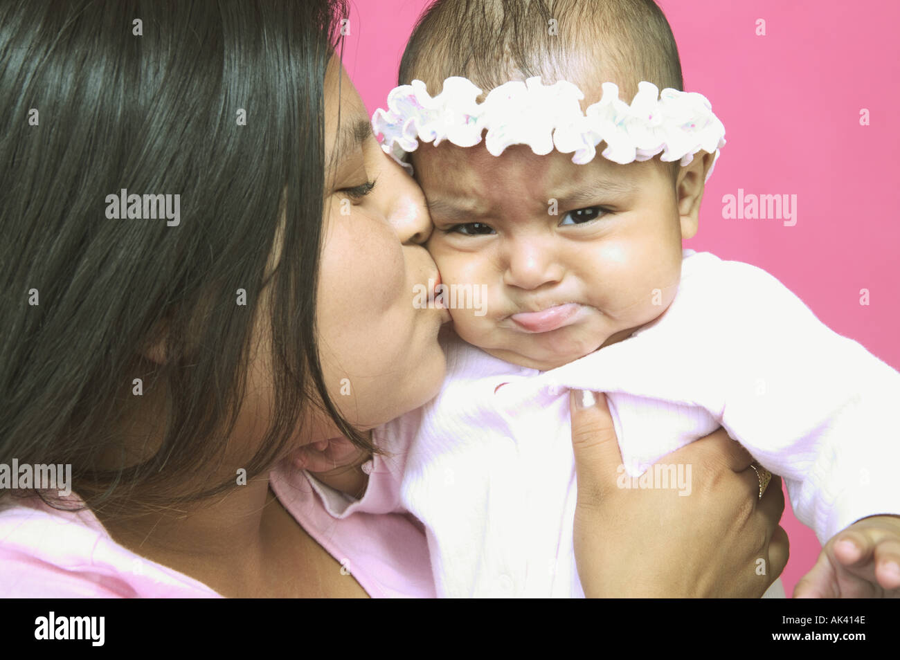 Young mother kissing her baby daughter on the cheek Stock Photo