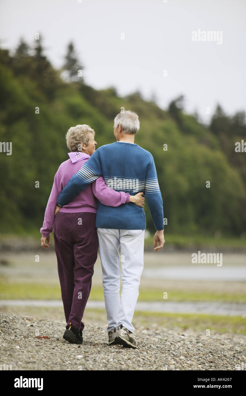 Couple walking on the beach with their arms around each other Stock Photo