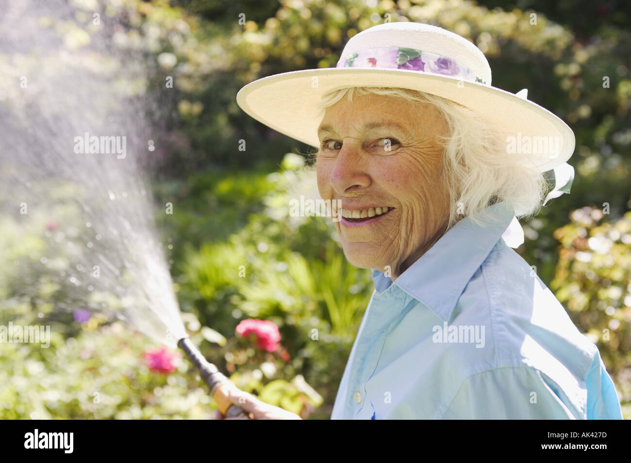 Senior woman watering her garden Stock Photo