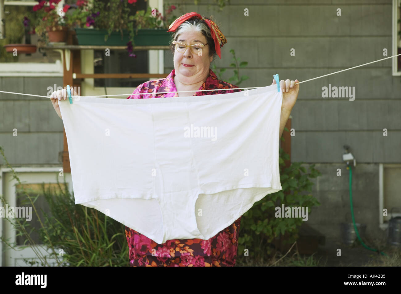 Woman hanging oversized underwear on a clothesline Stock Photo