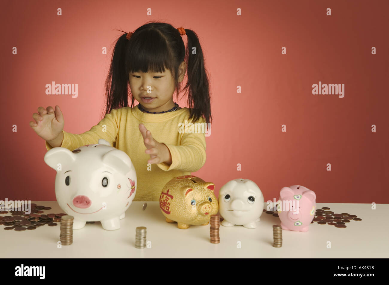 Child Cash Stack Little girl with stacks of coins and piggybanks Stock Photo - Alamy