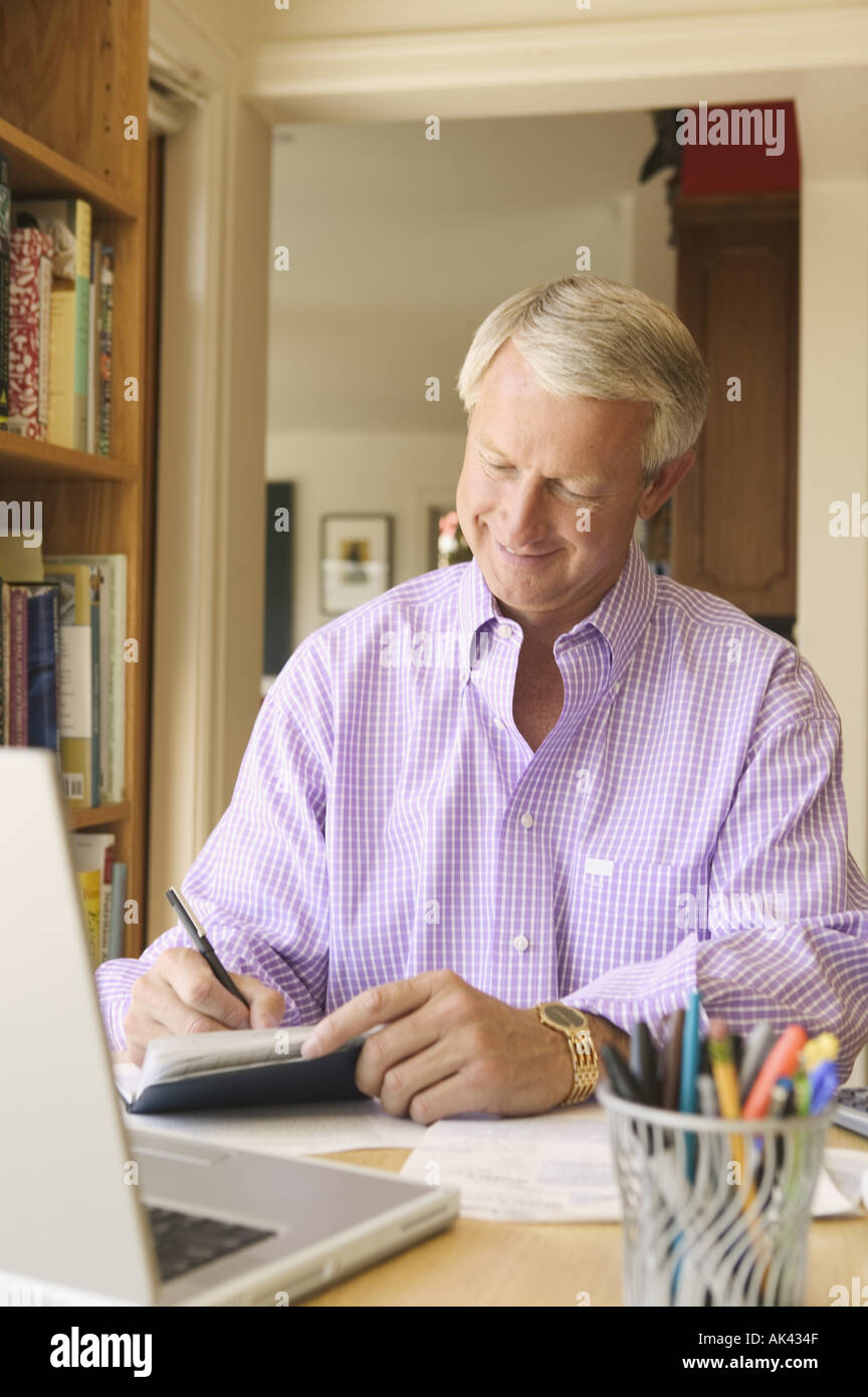 Man writing checks in his home office Stock Photo