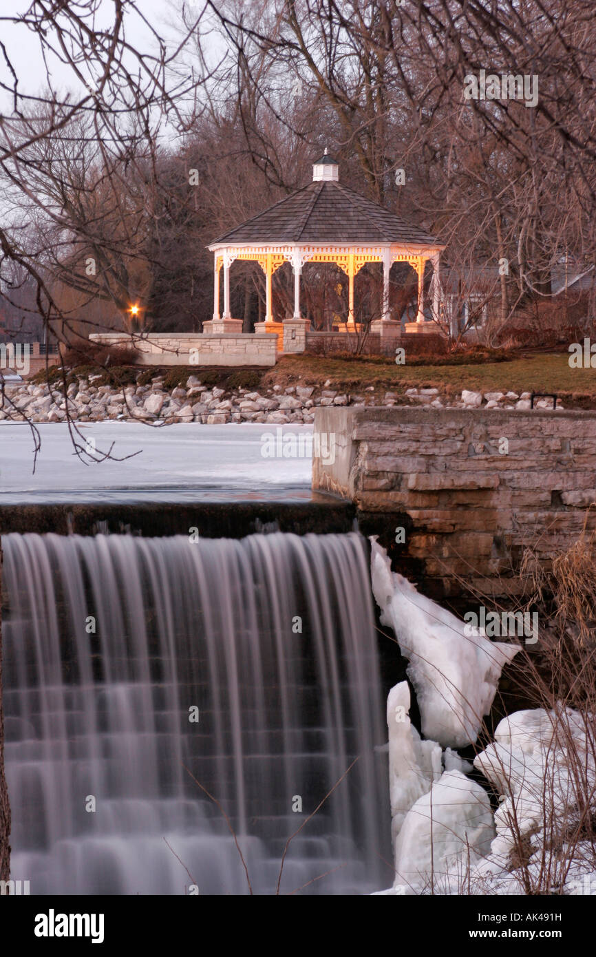 A gazebo in the park along the mill pond and waterfall in Midwest America Menomonee Falls Wisconsin Stock Photo
